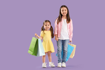 Poster - Cute little Asian happy sisters with shopping bags on purple background