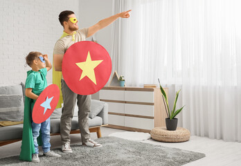 Sticker - Little boy and his father in superhero costumes with paper shields at home