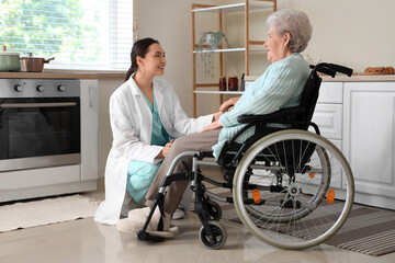 Poster - Physical therapist with senior woman in wheelchair holding hands at home