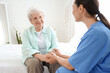 © Pixel-Shot - Physical therapist with senior woman holding hands in bedroom