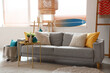 © Pixel-Shot - Light interior of living room with comfortable sofa, coffee table and surfboard