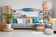 © Pixel-Shot - Light interior of living room with cozy sofa, coffee table, lamp and surfboard