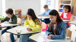 © Home-stock - Education concept. Group of diverse preteen students writing school test, noting lesson in their copybooks, sitting at desks in classroom