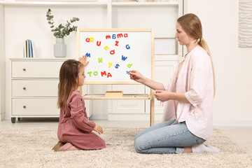 Canvas Print - Mom teaching her daughter alphabet with magnetic letters at home