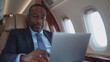 © SITI - Focused African American executive working on a laptop in a private jet, representing business travel and productivity
