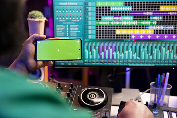Poster - Music producer operating on daw software in home studio and using an isolated display on smartphone, working on new songs. Professional technician adjusting volume levels with mixing console.