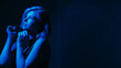 © golubovy - Hoping woman. Depression overcome. Female raising hands looking up expecting help mental mood disorder neon blue lights dark background empty space.