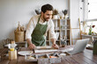 © sofiko14 - Man rolls clay with rolling pin in a bright and cozy pottery studio. He is concentrated on his work, surrounded by various pottery tools and equipment, creating a relaxed and creative atmosphere.
