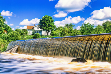 Canvas Print - Scenic view at a waterfall with a cottage by the water