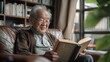 © visoot - A healthy and happy Asian elderly man reading a book in living room. Generative AI.