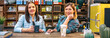 © David Pereiras - Portrait of two smiling female entrepreneurs looking at camera behind of counter in local motorbike shop. Banner of happy women colleagues working in store selling spare parts. Small business concept