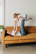 © Cavan Images - mom lays on couch while holding daughter up with her feet