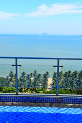 Wall Mural - Nha Trang city, Vietnam - October 15, 2023 : Overlooking the beautiful coast of Nha Trang with palm trees on the beach with deck chair and parasol. Beautiful white sand tropical beach in coastal city.