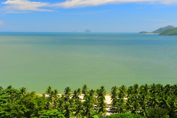 Wall Mural - Nha Trang city, Vietnam - October 15, 2023 : Overlooking the beautiful coast of Nha Trang with palm trees on the beach with deck chair and parasol. Beautiful white sand tropical beach in coastal city.