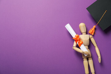 Wall Mural - Wooden statuette of a man with a graduation hat and diploma.