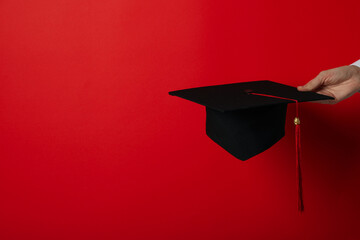 Poster - The hat of a university graduate, in his hands.