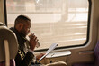 © tunedin - Stylish businessman with reusable cup and documents in a train