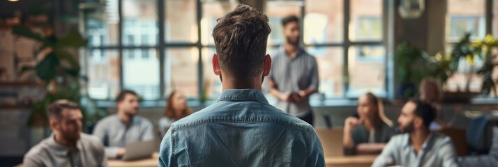 Wall Mural - A man stands in front of a group of professionals, leading a brainstorming session in a modern office space