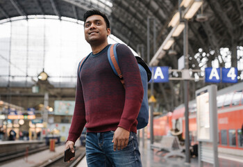 Wall Mural - Man with smartphone waiting for the train at the train station