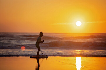 Wall Mural - Happy children, boys, playing on the beach on sunset, kid cover in sand, smiling, laughing