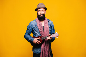 Canvas Print - Portrait of a bearded young man in studio holding ukulele