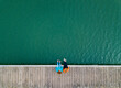 © tunedin - Two friends sitting side by side on jetty, Valdemurio Reservoir, Asturias, Spain