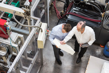 Top view of two men in factory shop floor talking about product