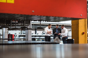 Wall Mural - Three men sharing tablet on factory shop floor