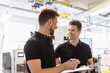 © tunedin - Two men with clipboard talking in factory