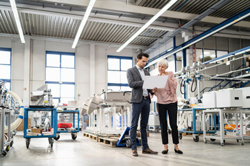 businessman and senior woman looking at plan in a factory