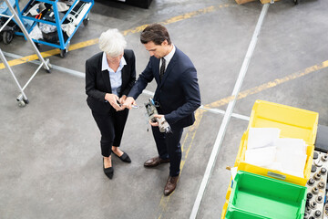 Canvas Print - Businessman and senior businesswoman examining workpiece in a factory