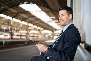 Sticker - Smiling businessman with tablet waiting on station platform