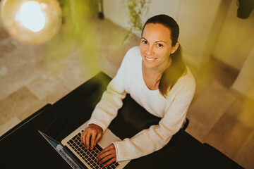 Poster - Smiling woman sitting with laptop at kitchen island