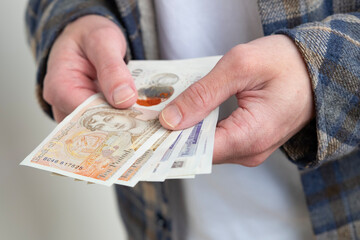 male hands holding money, counting English pound sterling bills, rejoices in success, anticipates what to spend, encouraging good financial behavior, economic awareness