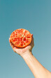 © tunedin - Arm of woman holding halved pomegranate