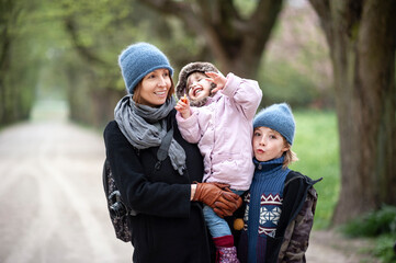 Wall Mural - Portrait of happy mother with son and little daughter in a park