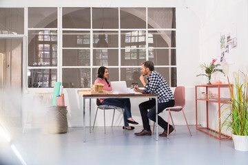 Poster - Smiling colleagues sitting at table in an architect's loft office