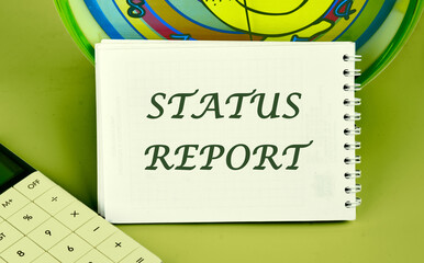 STATUS REPORT text on a notepad on the background of a clock next to a calculator