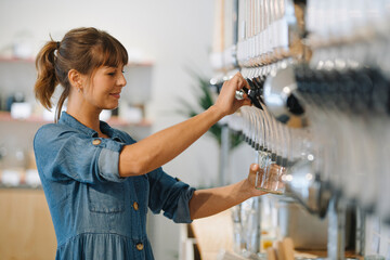 Young businesswoman filling grain in glass jar while standing in cafe