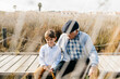 © tunedin - Grandfather sitting with his grandson on boardwalk relaxing