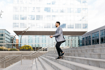 Canvas Print - Casual young businessman walking down stairs in the city