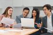 © PRIME STOCK LAB - Business professionals collaborate on project using laptop and documents.