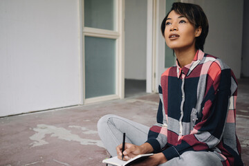 Poster - Woman sitting on cracked floor with notebook