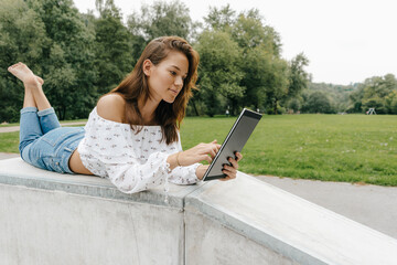 Poster - Young woman using lying in a skatepark using a tablet