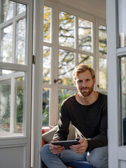 Wall Mural - Portrait of man using tablet in sunroom at home