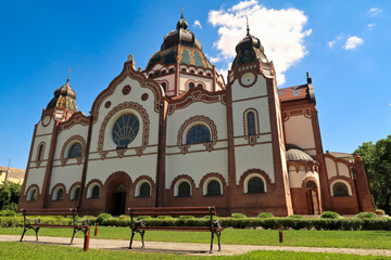 Wall Mural - The entire facade around the side entrance of the Synagogue of Subotica on a sunny day, two little benches are standing in the foreground, Subotica, Serbia