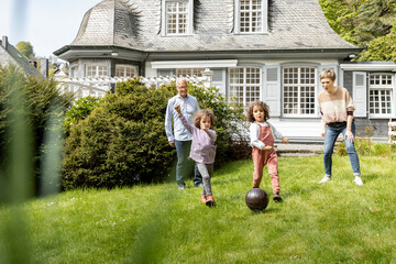 Wall Mural - Happy extended family playing football in garden