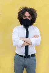 Wall Mural - Businessman wearing face mask and eyeglasses standing with arms crossed against wall