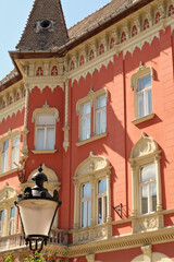 Wall Mural - The facade of the Vojnic Palace building with a bay window, tower and a street light, lamp, lantern in the foreground, city center of Subotica, Serbia