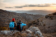 © tunedin - Male and female hikers enjoying sunset while sitting on rock mountain during vacation
